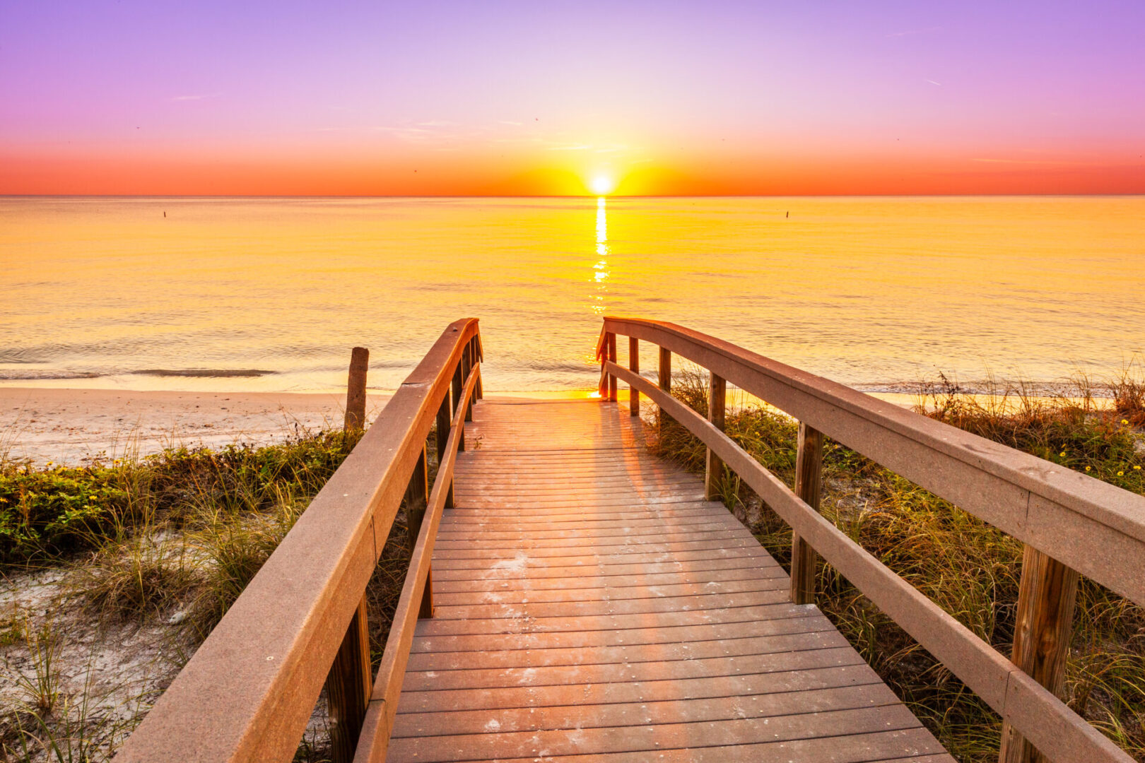 A boardwalk leading to the beach at sunset.