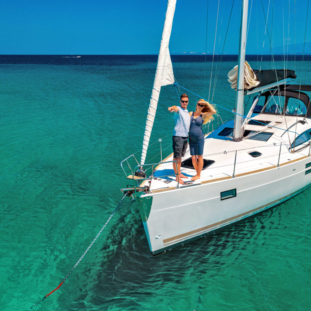 A couple is standing on the bow of their boat.